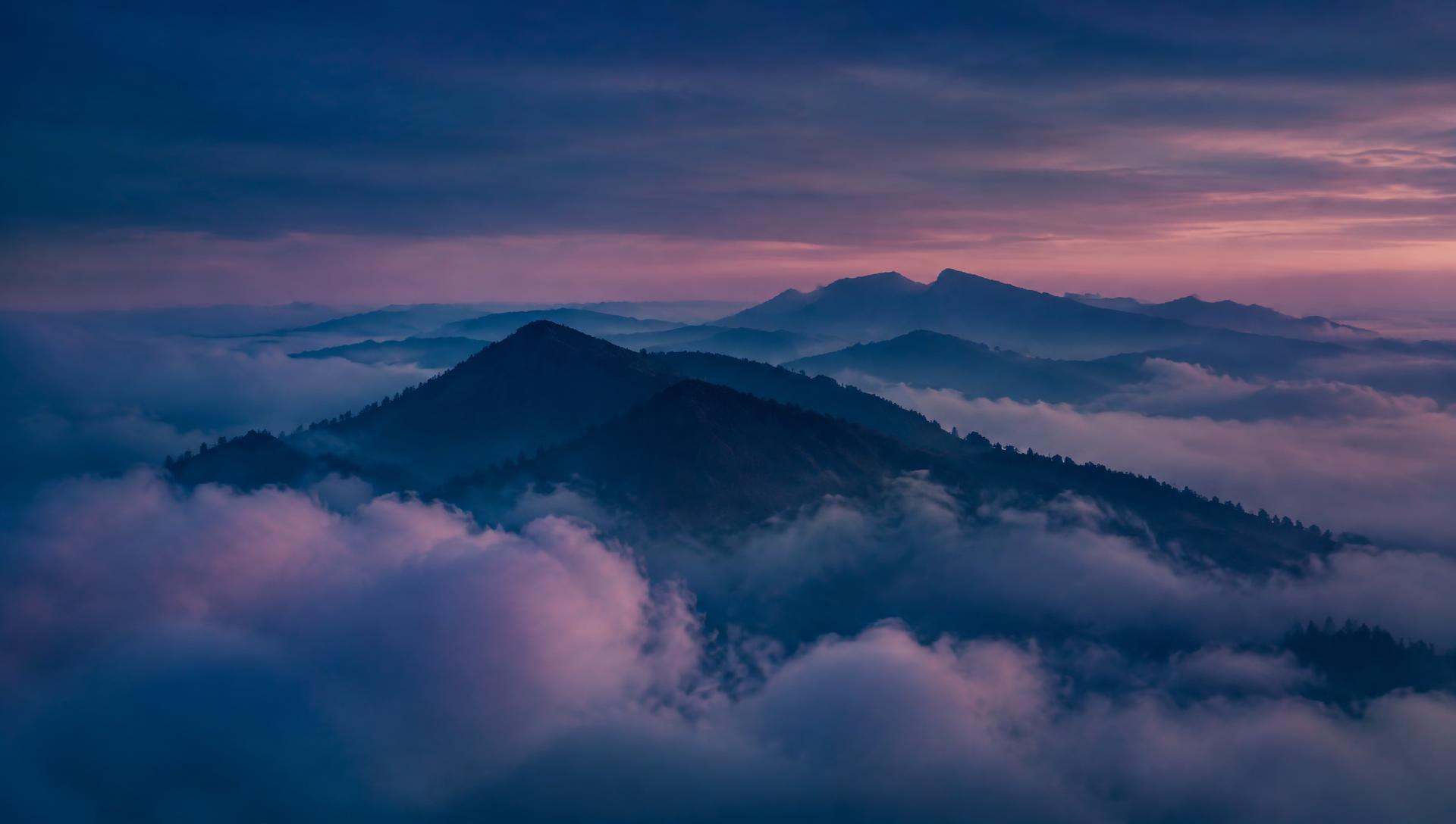 Mountain ridge rising through clouds